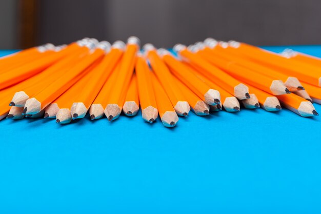 Bunch of orange pencils on blue close up