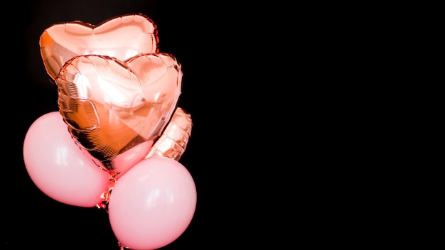 Bunch of pink color heart shaped foil balloons isolated on black background. Love. Holiday celebration. Valentine's Day party. Element of decorations for Birthday party, wedding or festival.