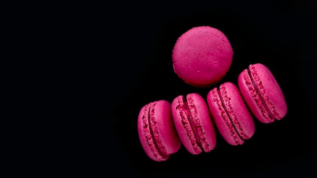 A bunch of pink macaroons on a black background