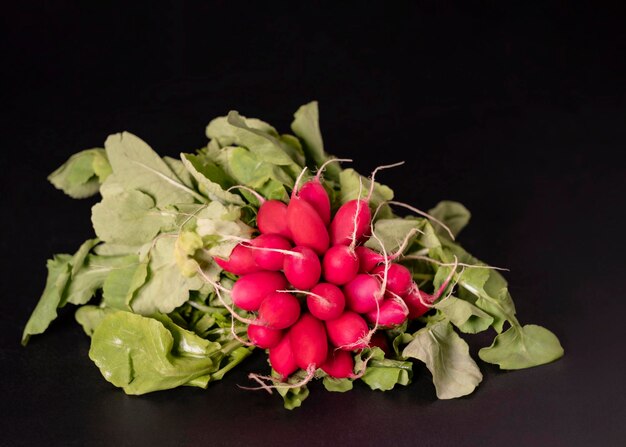 A bunch of radishes with green leaves on a black background