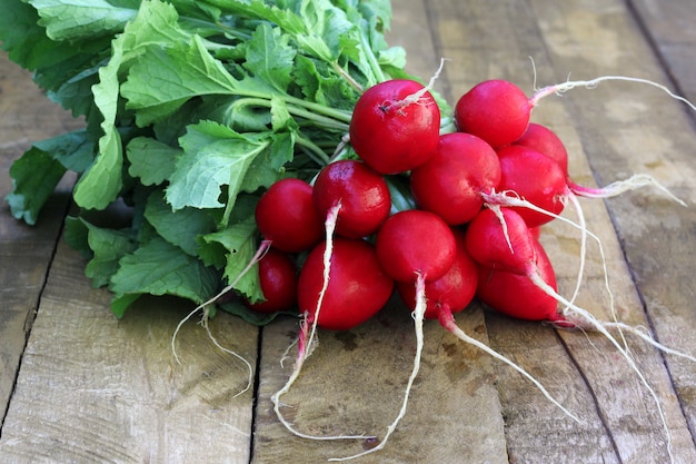 A bunch of radishes with tops on wooden flooring