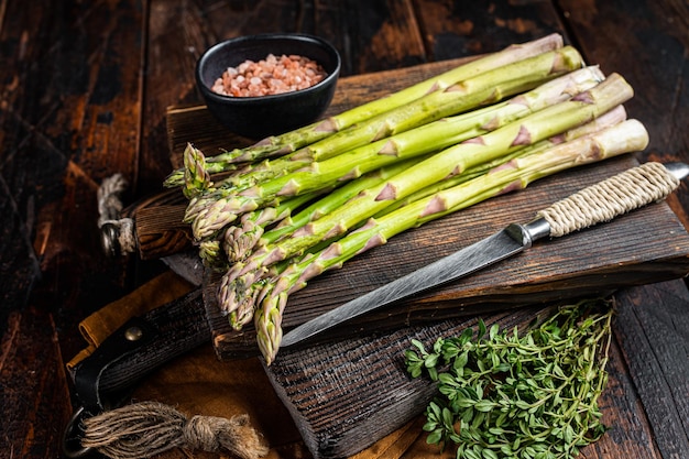 Bunch of Raw green asparagus on a wooden cutting board Wooden background Top view