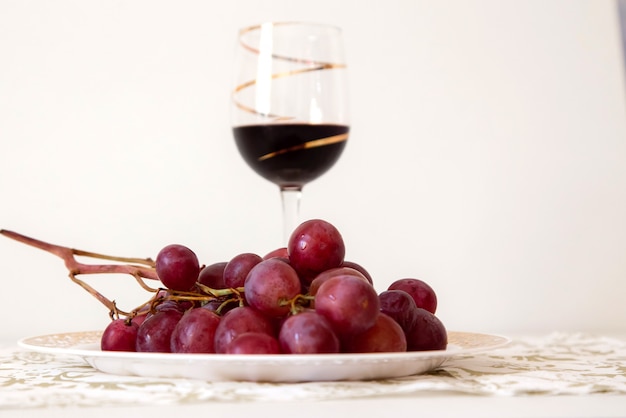 Bunch of red grapes with a glass of red wine in the background 