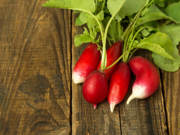 A bunch of red radishes on a wooden background