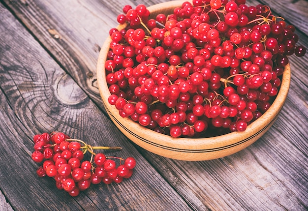 Photo bunch of red viburnum in a wooden bowl