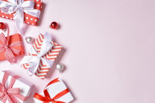 A bunch of red and white gifts on a pink background. Flat lay, top view, copy space.