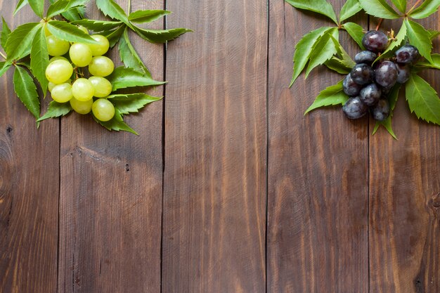 Mazzo di uva rossa e bianca sul fondo della tavola in legno