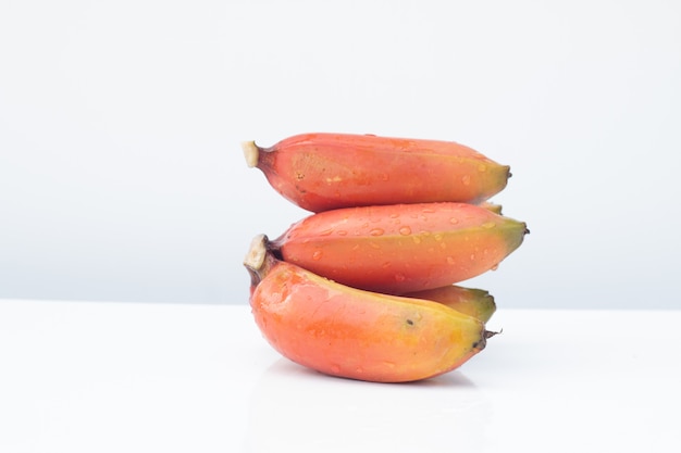 Bunch of ripe Cavendish banana or red bananas fruit on white table and white background