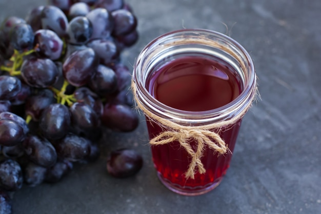 A bunch of ripe grapes and a glass of grape juice