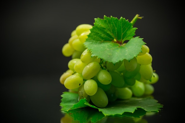 A bunch of ripe green grapes with leaves isolated on a black background