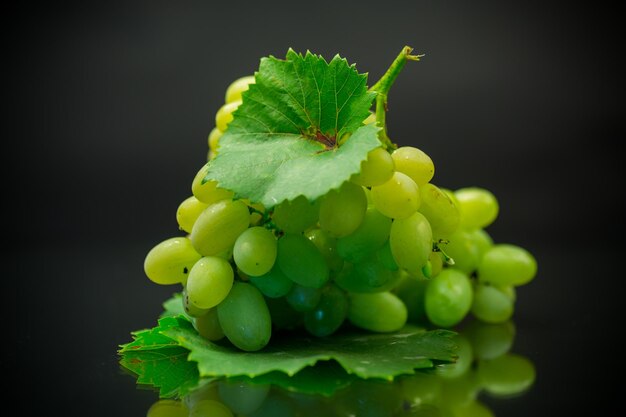 A bunch of ripe green grapes with leaves isolated on a black background