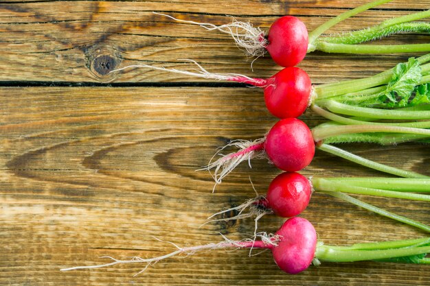 Photo a bunch of ripe red radishes on a wooden background