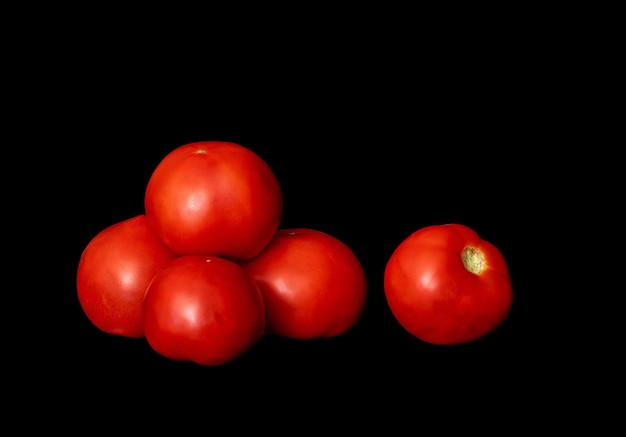 Bunch of ripe red tomatoes on a black backgroundxA