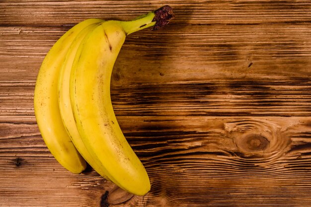 Bunch of the ripe yellow bananas on rustic wooden table. Top view