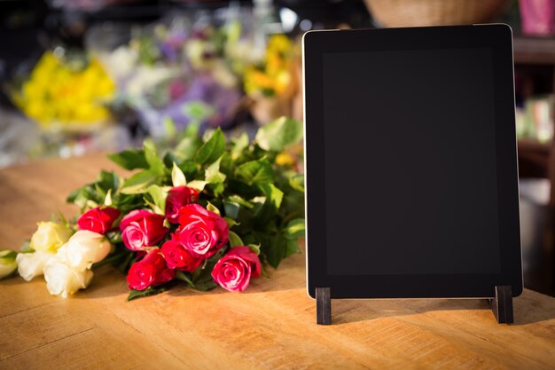 Bunch of roses and digital tablet on the wooden table