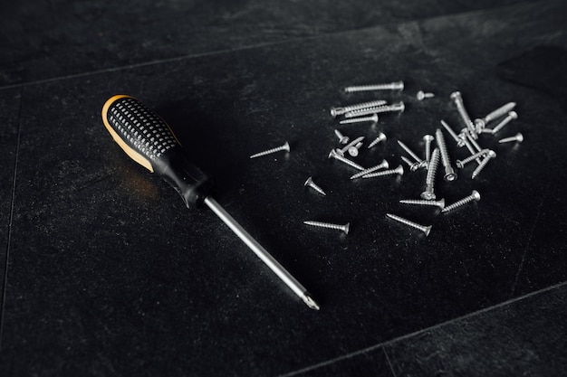 A bunch of self-tapping screws on the table. On a dark background.