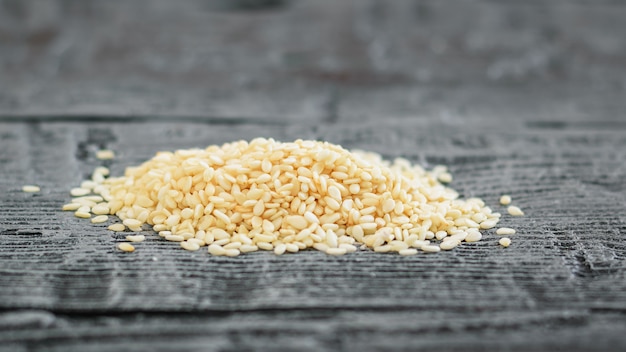 A bunch of sesame seeds on a dark wooden table