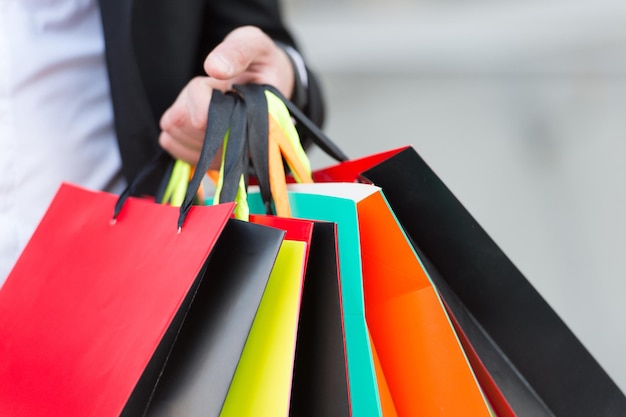 Bunch of shopping bags in male hands outdoor, close up. Plan your purchases in advance. Shopping tips. Successful shopping expedition. What a waste. Buy with list to not overspend and waste time.