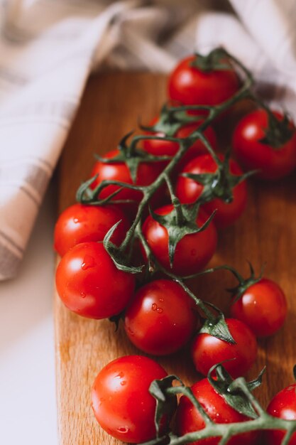 Bunch of small wet tomatoes on kitchen wooden desk and towel making dry and ready for salad