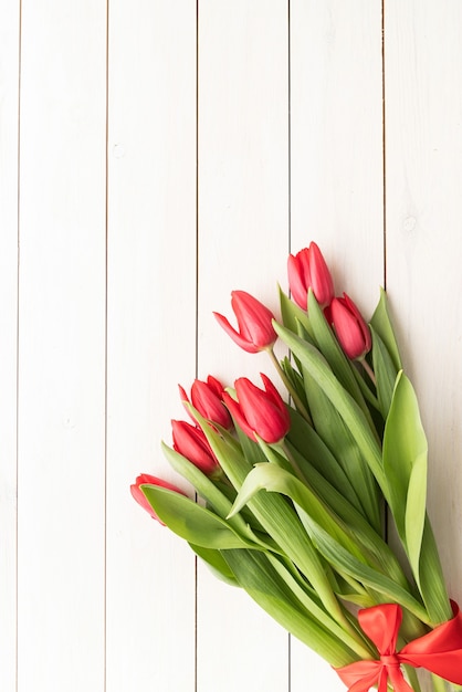 Bunch of spring tulips over white wooden background, top view flat lay