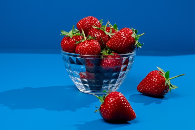 Bunch of strawberry in bowl on blue wall