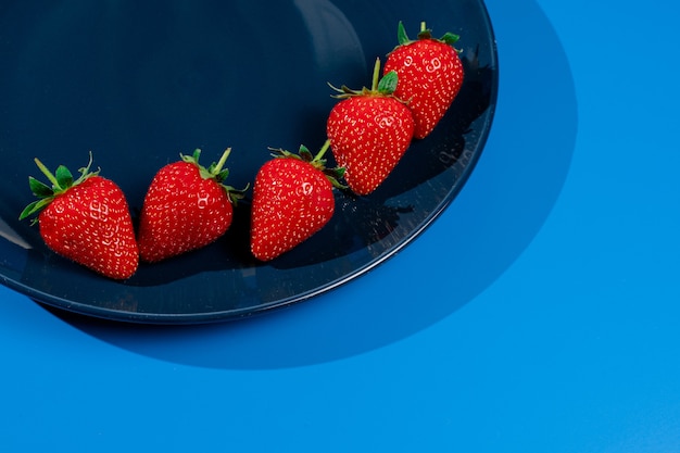 Bunch of strawberry on plate on blue wall