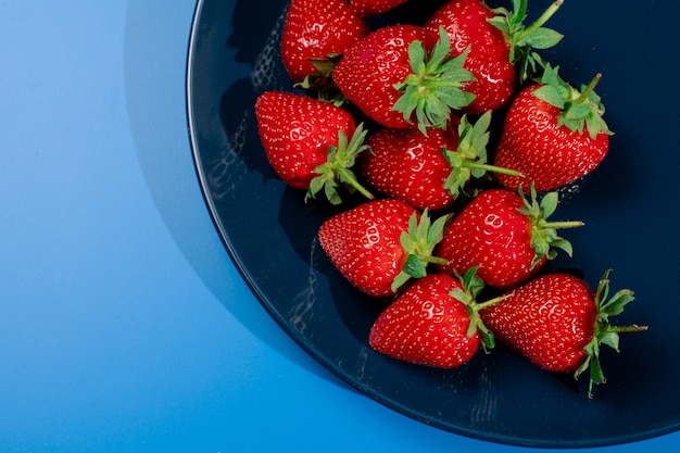 Bunch of strawberry on plate on blue wall