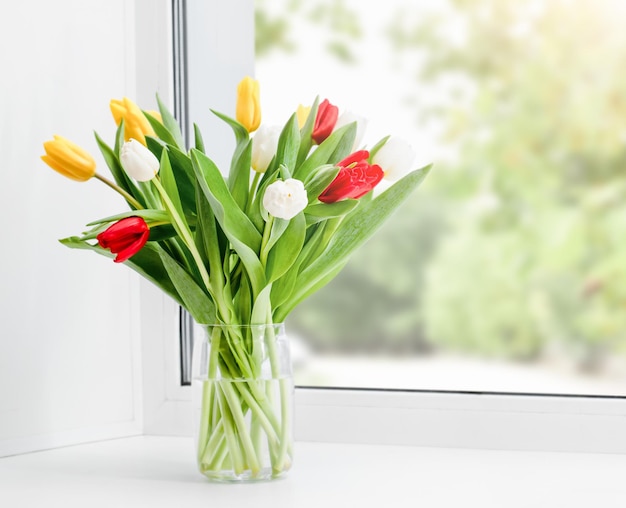 A bunch of tulips in a vase on the windowsill