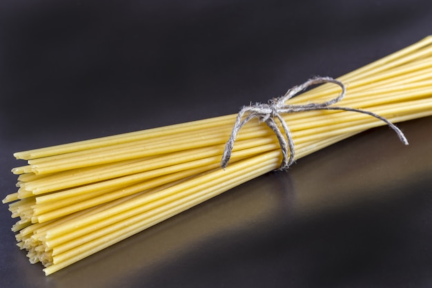 Bunch of uncooked whole wheat spaghetti pasta closeup.