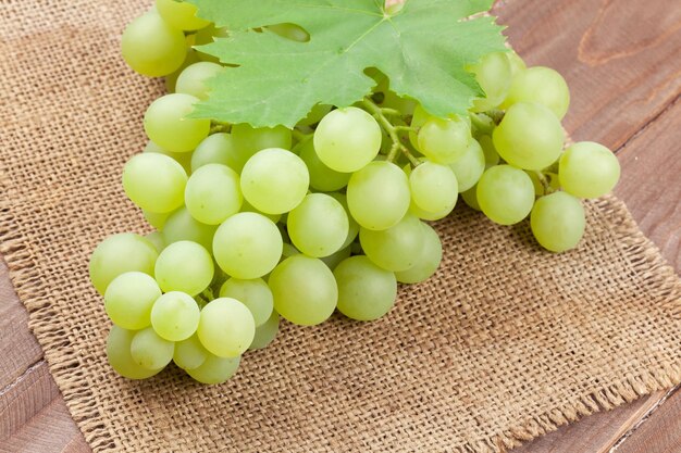 Bunch of white grapes with leaves over burlap