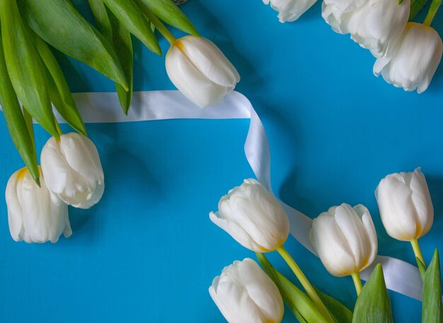 a bunch of white tulips with a white ribbon tied around them.