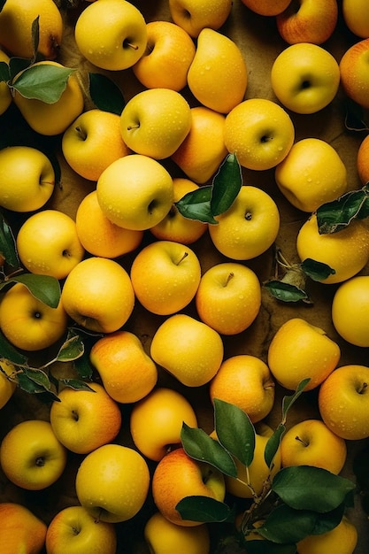 A bunch of yellow apples with green leaves on them