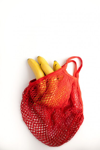 bunch of yellow bananas in a red cotton string bag on a white. Zero waste. concept of conservation of nature on the planet