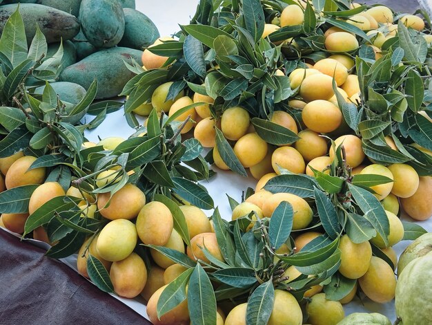 Bunch of Yellow Fruits with Green Leaves for Sale at Market Stall