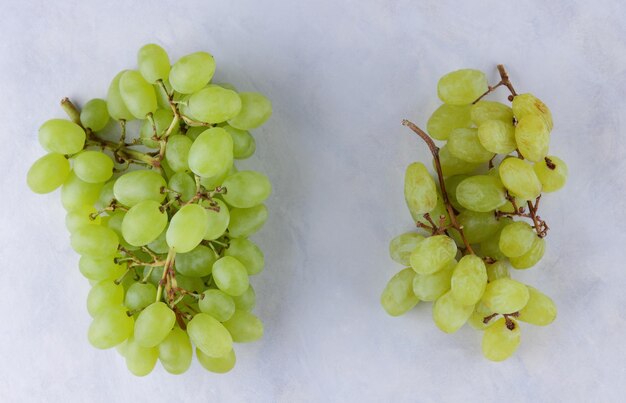 A bunch of young juicy grapes and a bunch of dried grapes on a light background Closeup View from above