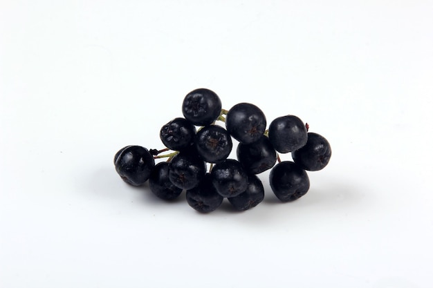 Bunches of black chokeberry berries with leaves on a white background. Chokeberry