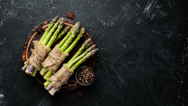 Bunches of fresh green asparagus on a black background Healthy food Top view Free space for your text