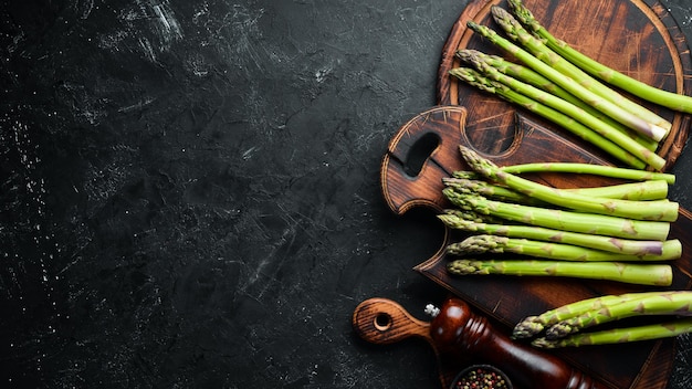 Bunches of fresh green asparagus on a black background Healthy food Top view Free space for your text