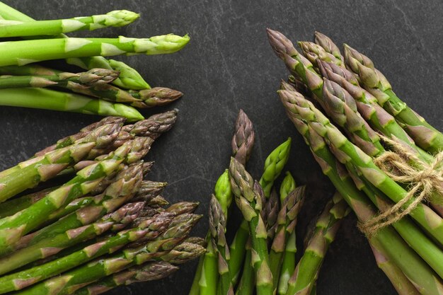 Photo bunches of fresh green asparagus on dark background top view