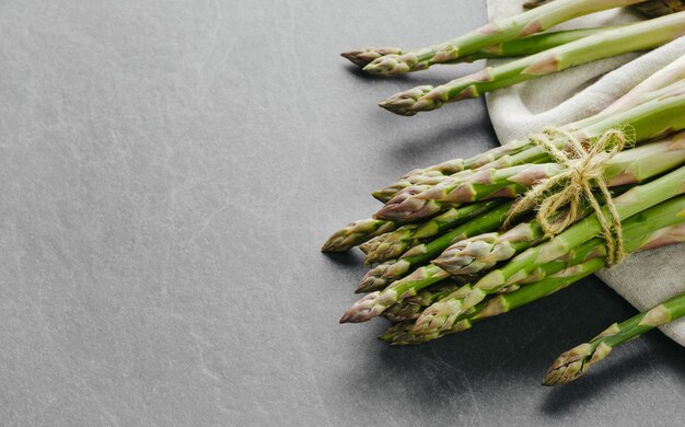 Photo bunches of fresh green asparagus on dark background top view