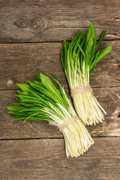 Grappoli di raccolto fresco di primavera ramson porro selvatico fragranti foglie speziate su tavola di legno d'epoca