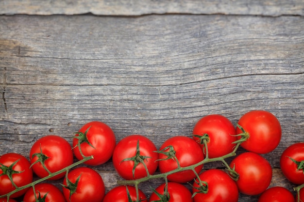 Bunches of red cherry tomatoes on wooden surface with copyspace