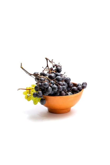 Bunches of ripe grapes in a brown plate on a white background