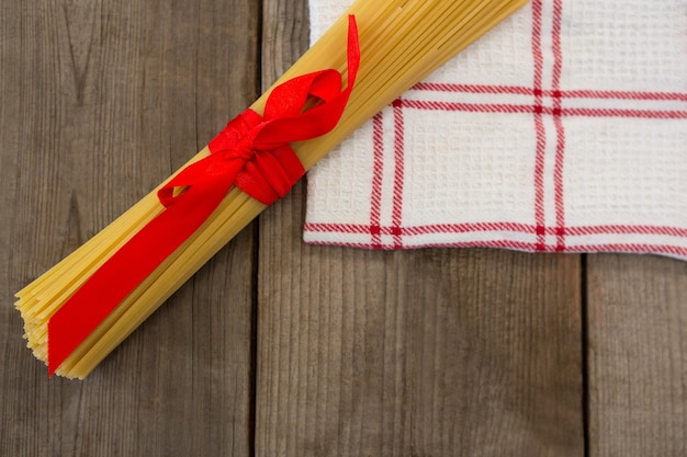 Bundel van rauwe spaghetti gebonden met rood lint op servet