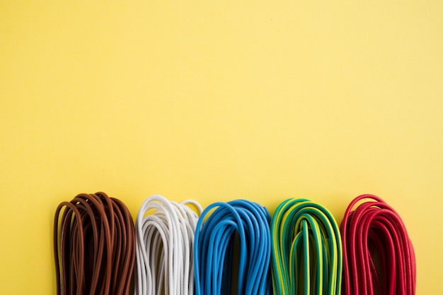 Photo bundle of colorful electronic wire over plain yellow backdrop