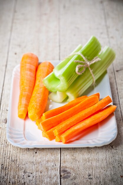 Bundle of fresh green celery stems and carrot