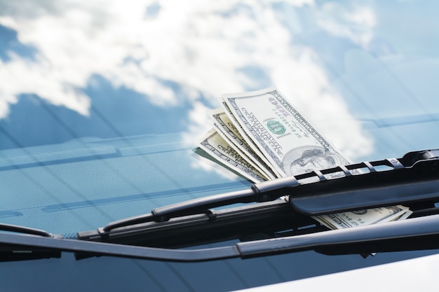 Bundle of US dollar banknotes left on a car under the car wiper on a windscreen