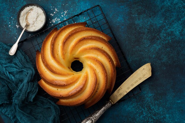 Foto bundtcake met suikerglans en kokos op donkerblauwe oude concrete oppervlakte. selectieve aandacht.