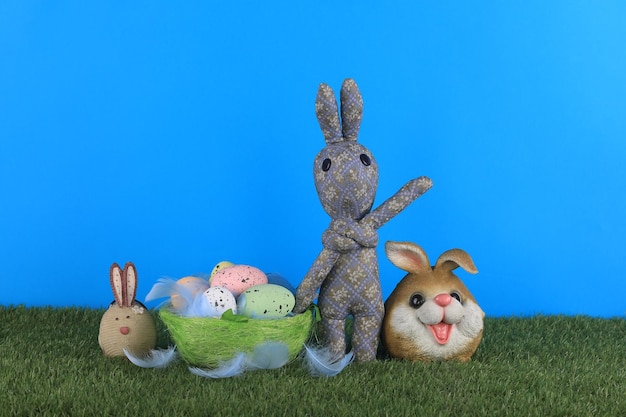 A bunny and a basket of eggs are on a green lawn.