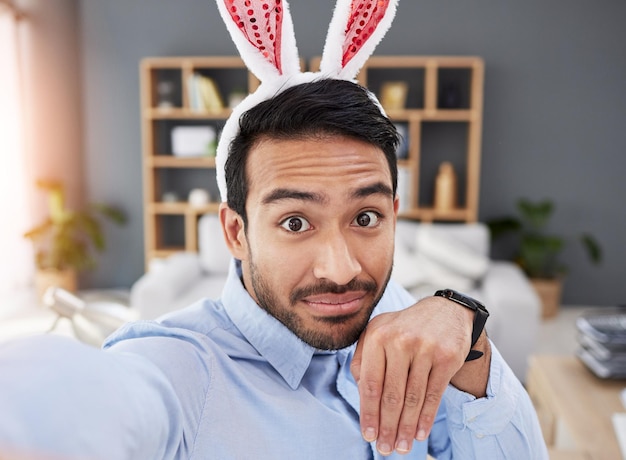 Bunny ears holiday and selfie with a man and remote work on easter with creative job Celebration happy and male professional from Spain feeling silly and goofy with comedy rabbit hat in a home